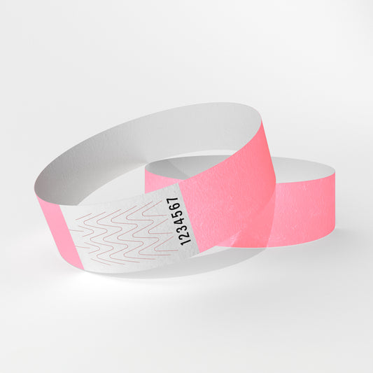 Das Bild zeigt zwei Tyvek-Kontrollarmbänder. Eines über dem anderen. Auf dem oberen Armband ist ein weißes Teil zu sehen, das ein Verschluss aus Klebstoff ist, der beim Abnehmen des Armbands reißt.